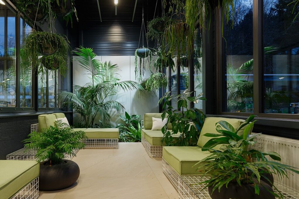Liege und Sitzmöglichkeiten in einem Innengarten, umgeben von Gefäßbepflanzungen und Hängepflanzen