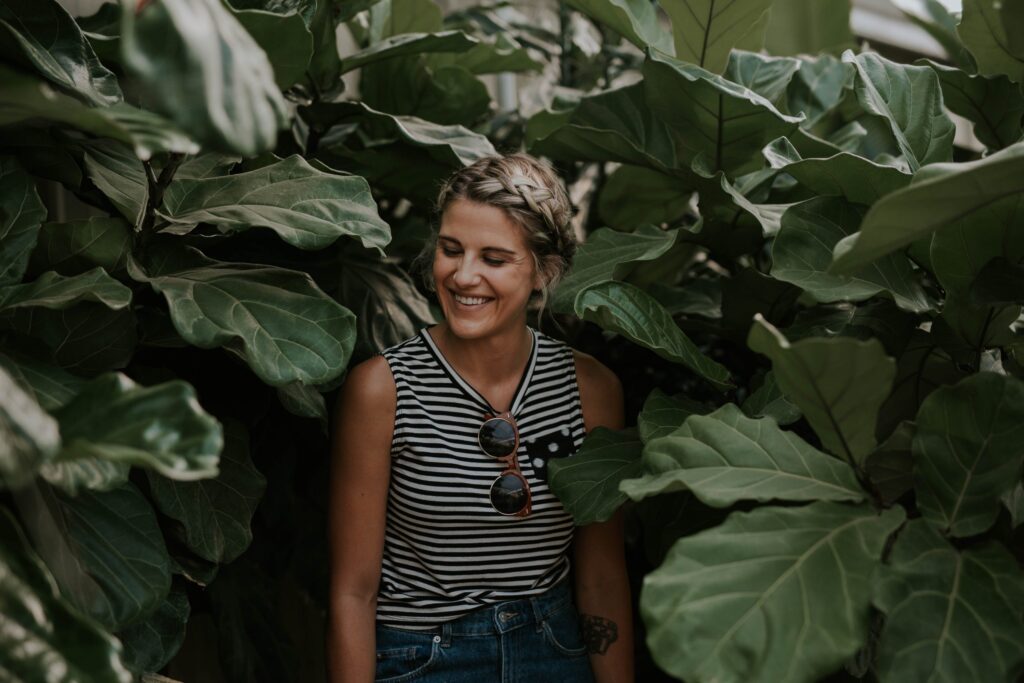 Lächelnde Frau zwischen Pflanzen mit großen Blättern